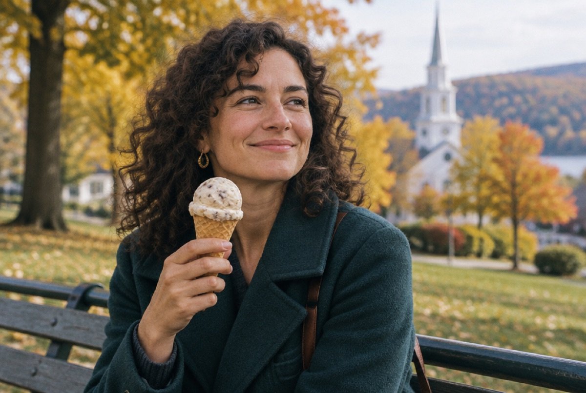 Woman enjoying an ice cream cone on a park bench in autumn